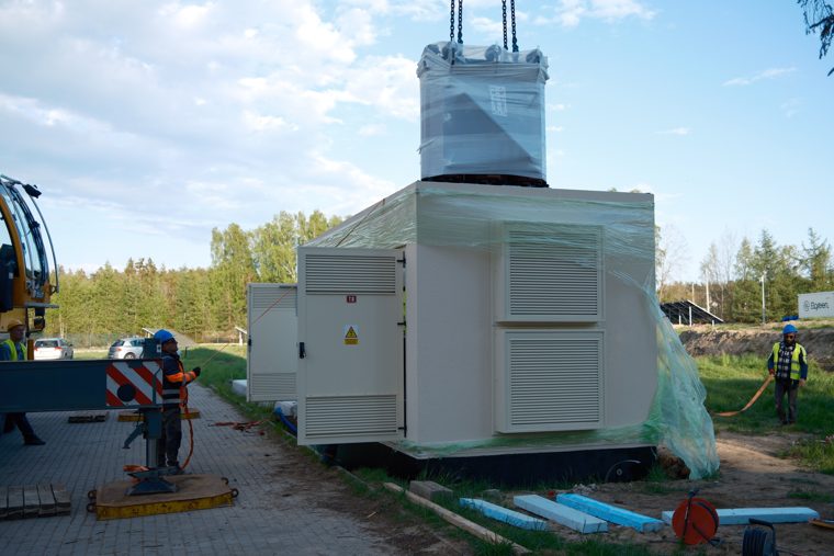 Opuszczanie transformatora dźwigiem na prefabrykowaną stację transformatorową