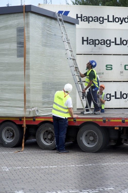 Dostawa elementów stacji transformatorowej na naczepie, w tle kontenery portowe